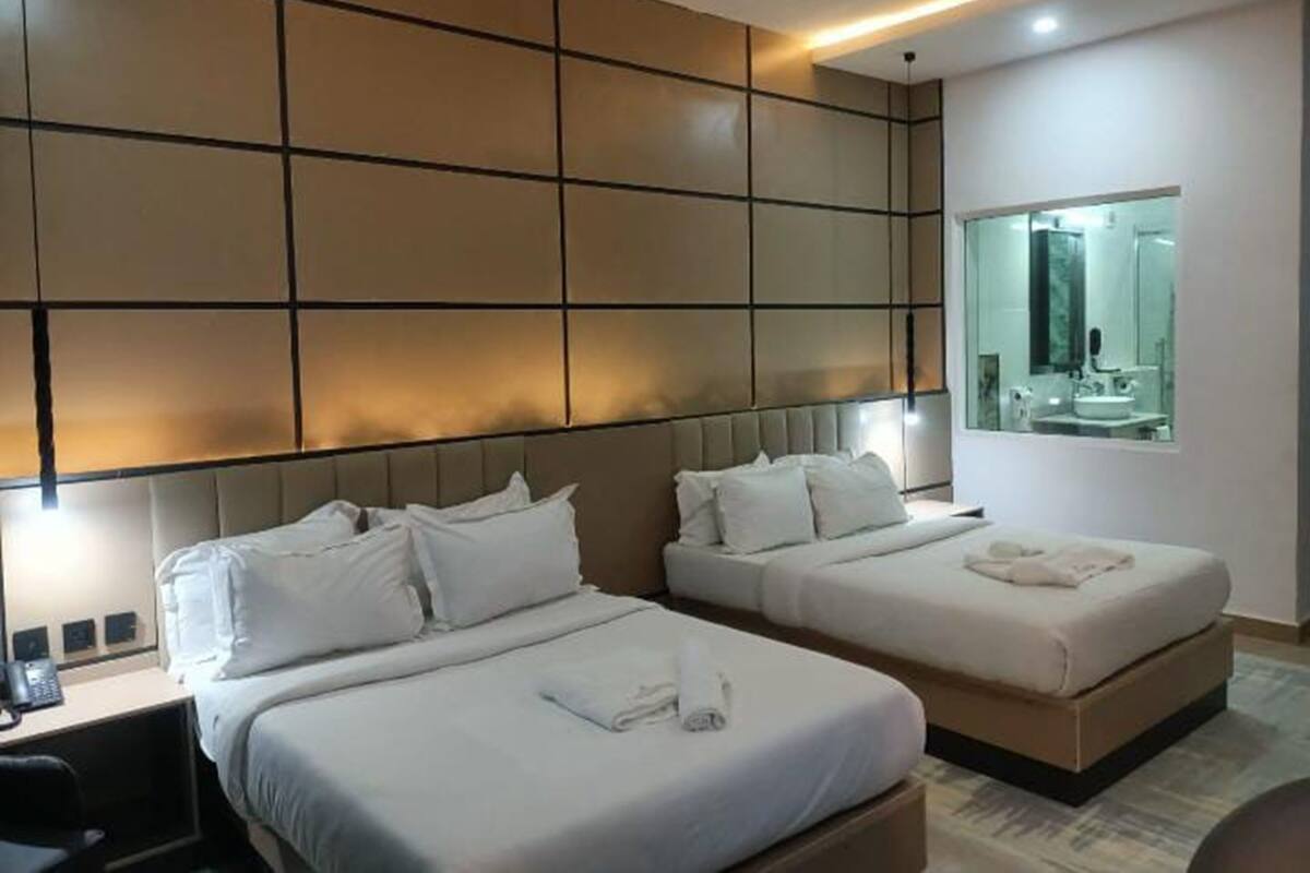 Une chambre d’hôtel avec deux lits, un bureau et un grand miroir.