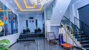 A modern hotel lobby with a reception desk, a digital kiosk, and a staircase. - G Pinnacle Signature Hotel (Ilorin)