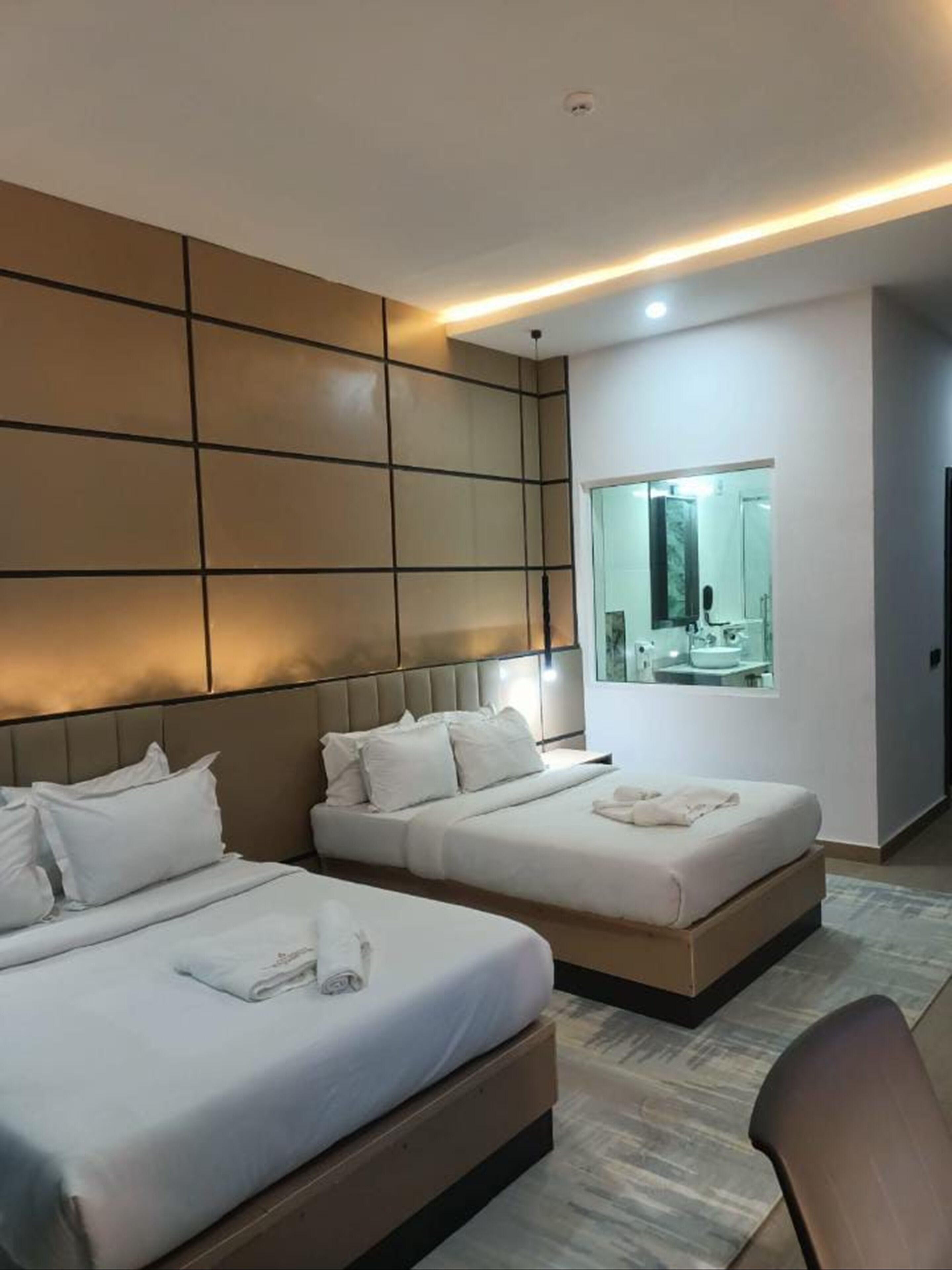 A hotel room with two beds, a large mirror, and a modern design.