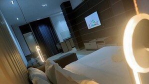 A modern hotel room with a large bed, a TV mounted on the wall, and a bedside table. - G Pinnacle Signature Hotel (Ilorin)