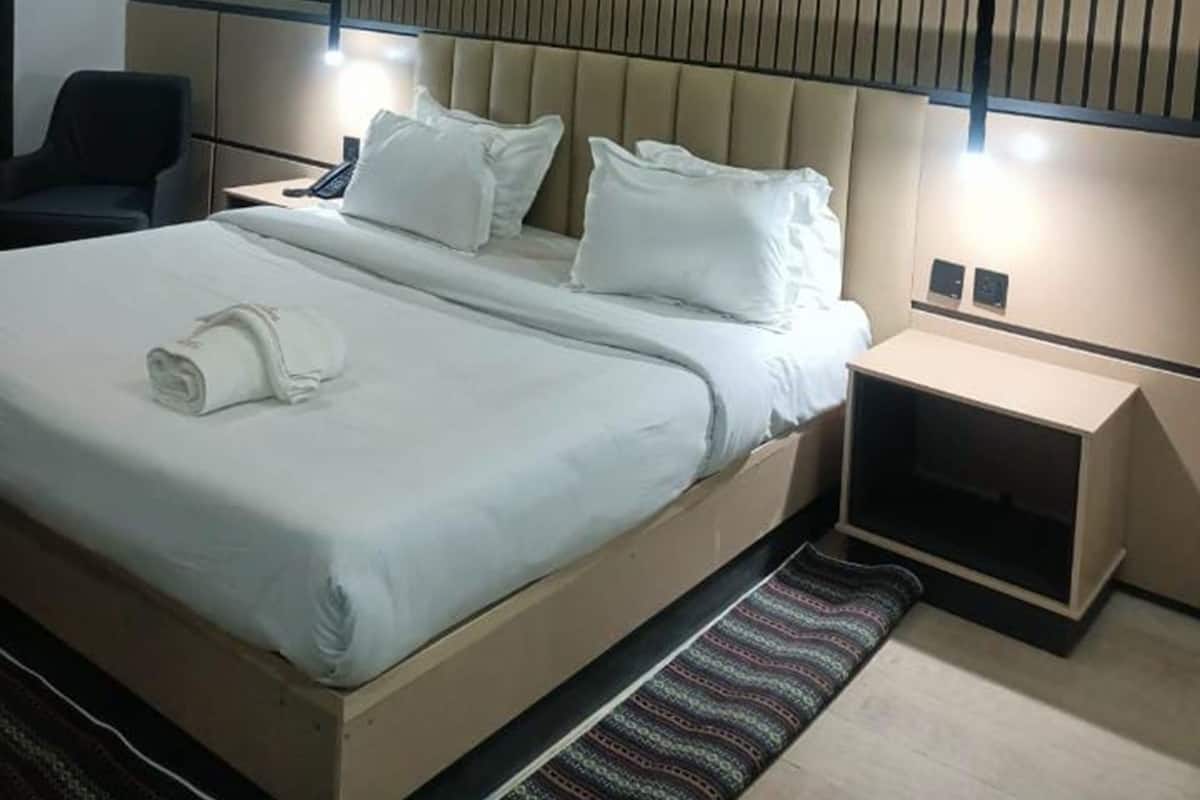 Une chambre d’hôtel moderne avec un grand lit, des tables de chevet et un mur recouvert de lambris en bois verticaux.