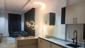 A modern kitchen with a built-in oven, a sink, and a dining area with a sofa and a coffee table. - G Pinnacle Signature Hotel (Ilorin)