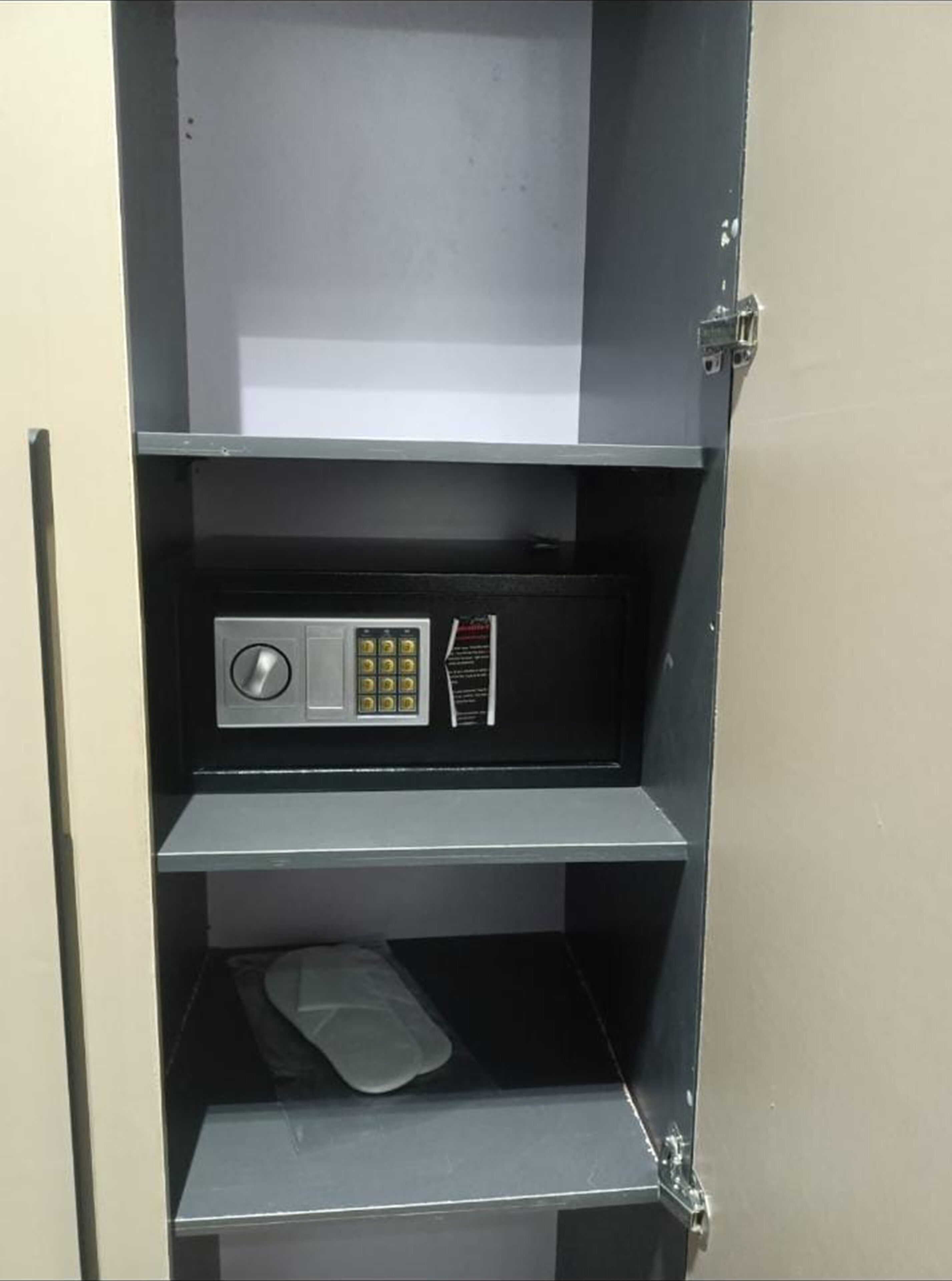 A metal safe deposit box with a keypad and a small shelf.