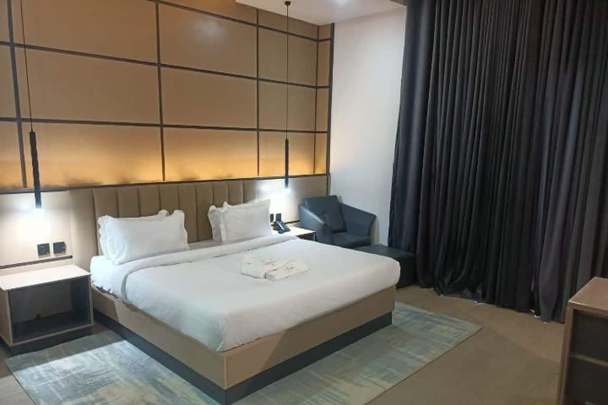 Une chambre d’hôtel moderne, dotée d’un grand lit, de tables de chevet, d’un bureau et d’une chaise.