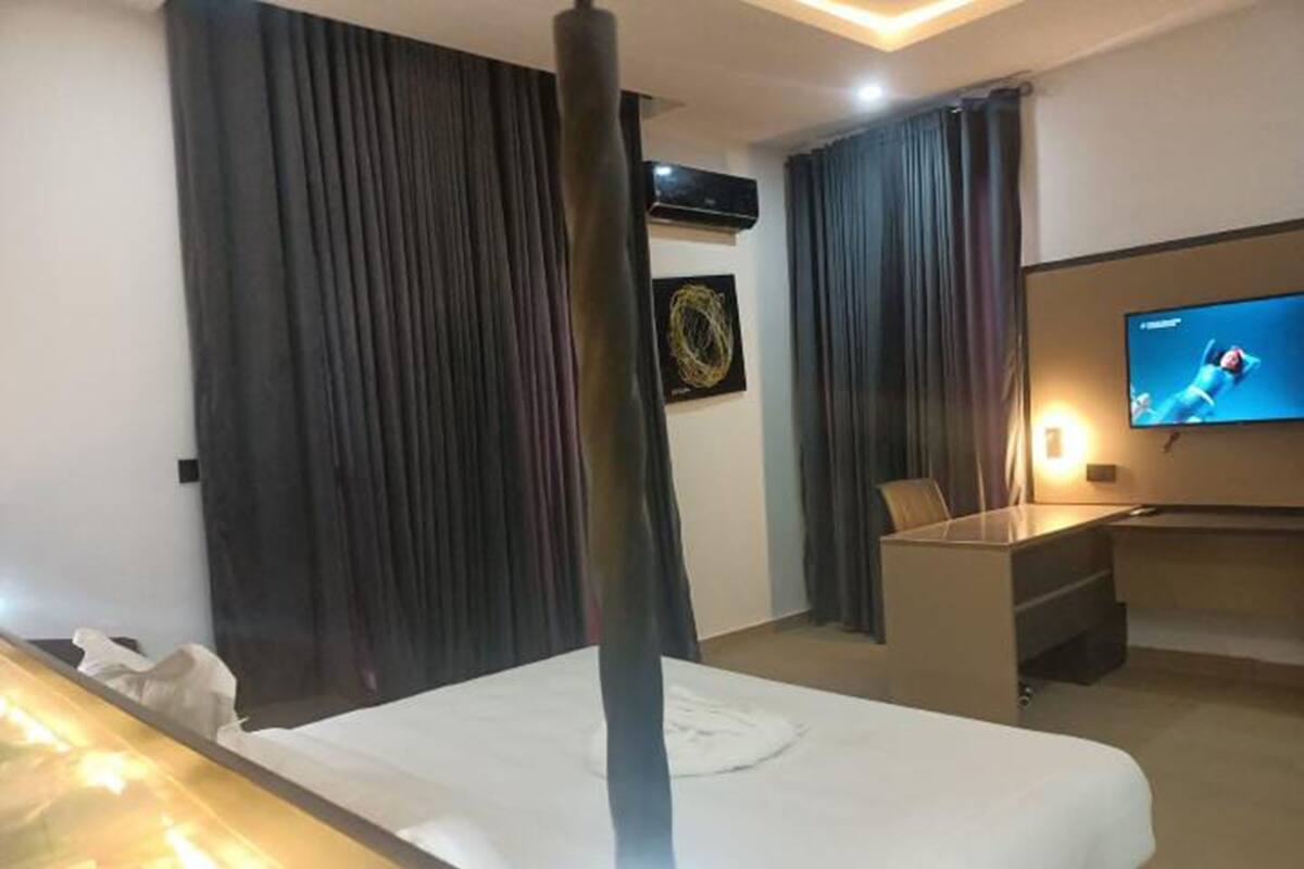 Une chambre d’hôtel avec un lit, un bureau, une télévision et des rideaux.