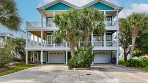A two-story beachfront house with a covered front porch, a garage, and a balcony on each floor. - 🌊Seaside Hugs-Close to the Ocean w/ Large Decks-Pet Friendly🌊 (Kure Beach)