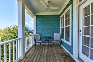 Eine überdachte Veranda mit Deckenventilator, zwei Stühlen und einem kleinen Tisch.