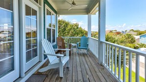 A covered porch with two Adirondack chairs, a table, and a ceiling fan. - 🌊Seaside Hugs-Close to the Ocean w/ Large Decks-Pet Friendly🌊 (Kure Beach)