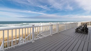 A wooden deck with white railings overlooking a beach. - Dune Crest - Southern Shores, Oceanfront, Pool, Hot Tub, Pool Table, Pets OK (Southern Shores)