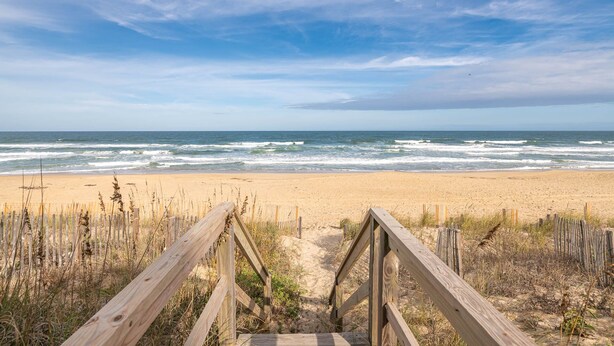 A wooden boardwalk leading to a sandy beach with ocean waves in the background. - Dune Crest - Southern Shores, Oceanfront, Pool, Hot Tub, Pool Table, Pets OK (Southern Shores)