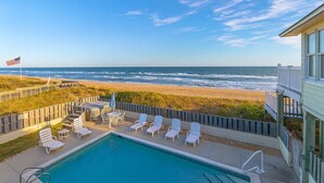 A pool area with lounge chairs and a view of the beach and ocean. - Dune Crest - Southern Shores, Oceanfront, Pool, Hot Tub, Pool Table, Pets OK (Southern Shores)