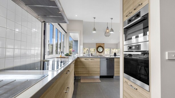 A modern kitchen with a stainless steel range hood, wooden cabinets, a dishwasher, and pendant lighting. - Limestone Views: Discover this farmhouse set in a bend of the Tambo River (Swan Reach)