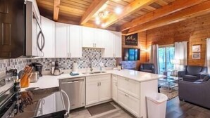 Une cuisine moderne avec des meubles blancs, un pare-feu en carrelage et un plafond en bois.