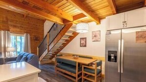 Un intérieur en bois comprenant une cuisine, un coin repas avec un banc et un escalier.