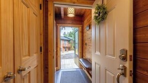 Un couloir en bois menant à une porte, avec un banc et une petite plante à proximité.