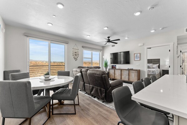 A spacious living area with a large dining table, comfortable seating, a ceiling fan, and a TV. - Dreamy Lagoon: Desert Color Lagoon + Beaches (St. George)