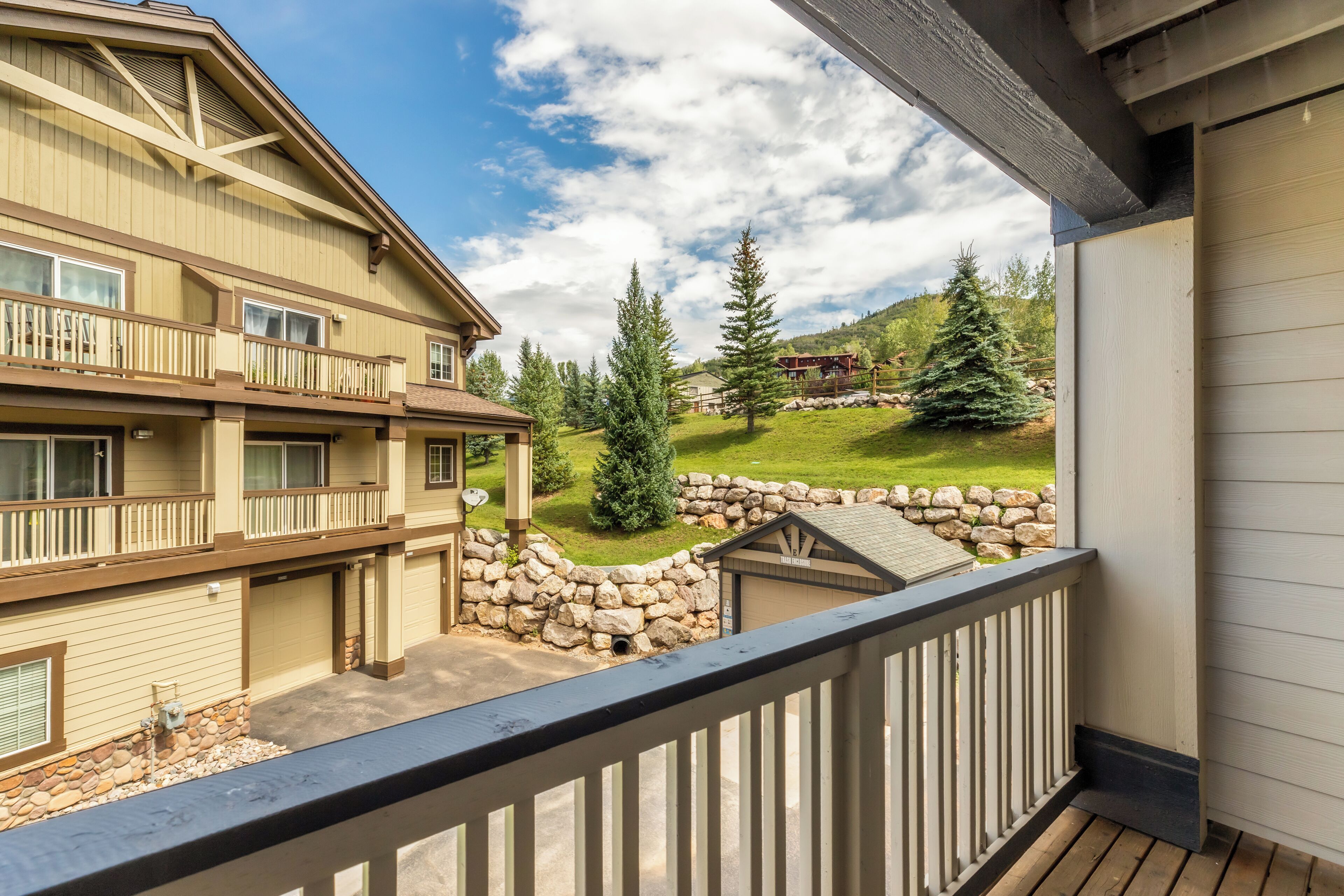 A multi-story building with balconies, a stone wall, and a view of a mountainous landscape.