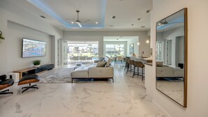 A spacious living area with a large sofa, a dining table, and a bar area. - Villa Summer Feeling - newly built, on water, pool & spa (Cape Coral)
