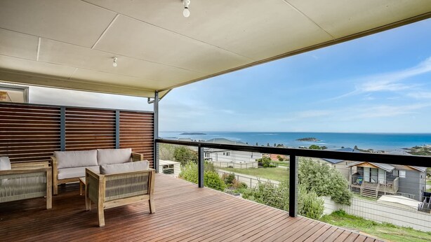 A balcony with a wooden floor, a sofa, and a view of the sea. - Seaview at the Bay - Wi-Fi and Linen Included (Encounter Bay)