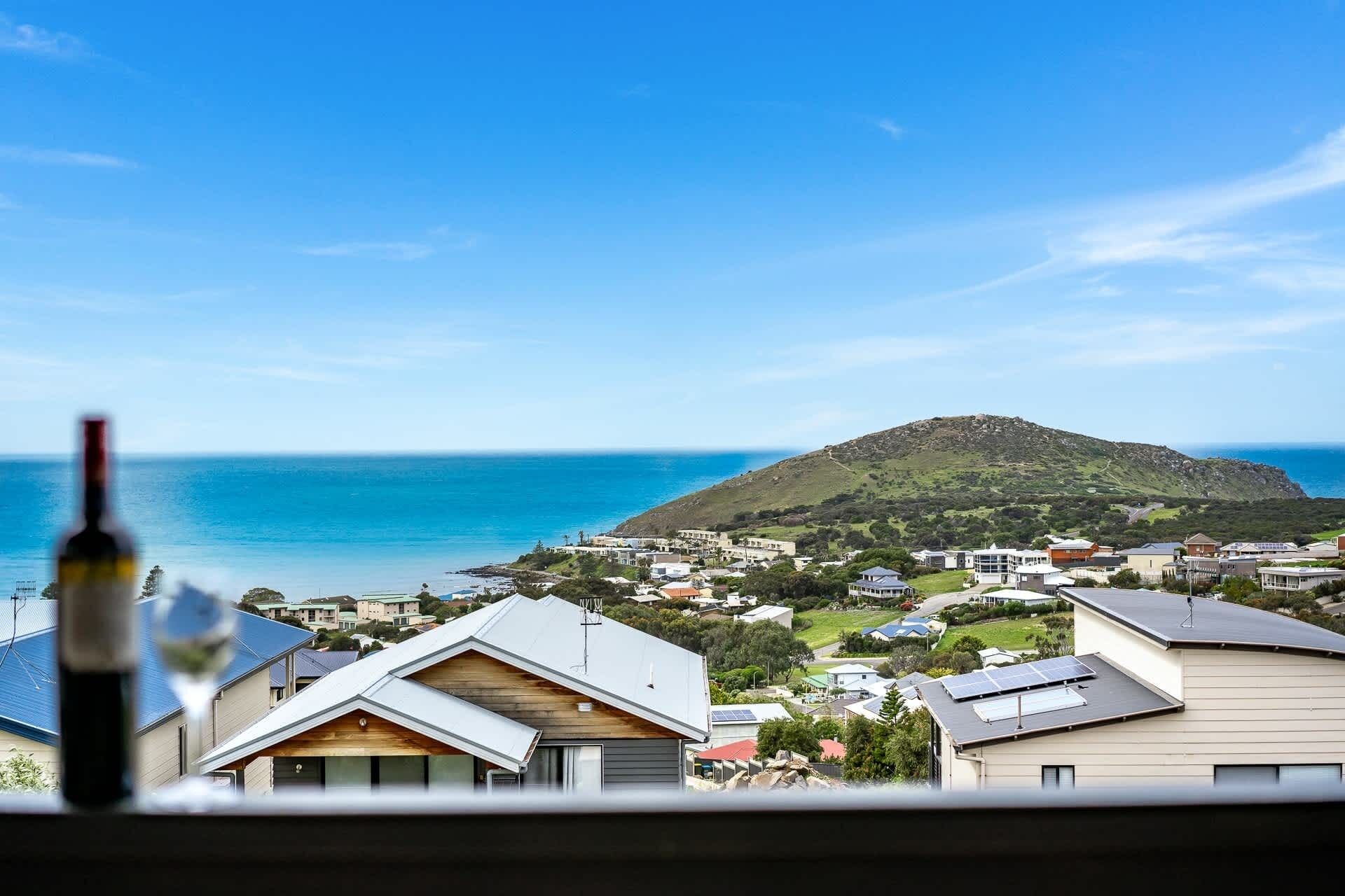 A coastal residential area with houses, a hill, and the ocean.