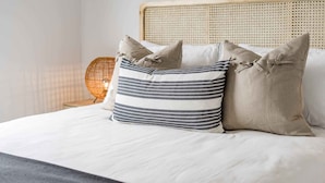 A bed with a white mattress, a woven headboard, and three pillows with different patterns. - Seaview at the Bay - Wi-Fi and Linen Included (Encounter Bay)