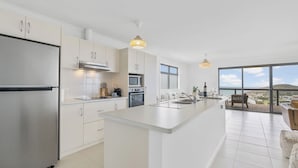A modern kitchen with a central island, stainless steel appliances, and a large window offering a view of the landscape. - Seaview at the Bay - Wi-Fi and Linen Included (Encounter Bay)