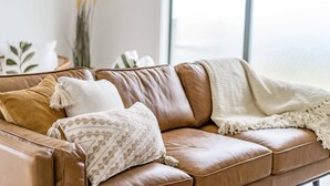 A brown leather sofa with patterned cushions and a white throw blanket. - Seaview at the Bay - Wi-Fi and Linen Included (Encounter Bay)