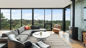 Een moderne woonkamer met een grote hoekbank, een ronde salontafel en een open haard.