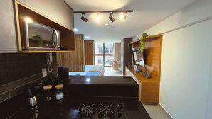 A modern kitchen with a built-in microwave, a coffee machine, and a gas stove. - Flat FM20 Vista Lateral - By Almare (João Pessoa)