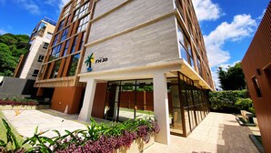 A modern building with a flat roof, large windows, and a sign reading "FLAT FM20". - Flat FM20 Vista Lateral - By Almare (João Pessoa)