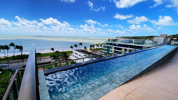A modern infinity pool with a clear view of the ocean and beach. - Flat FM20 Vista Lateral - By Almare (João Pessoa)