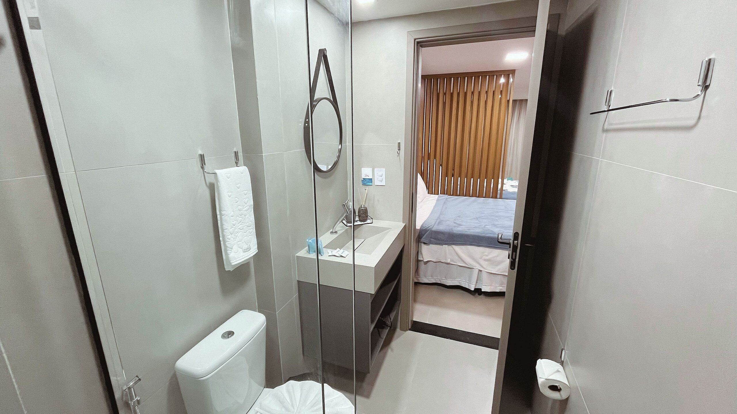 A compact hotel bathroom with a toilet, sink, and shower.