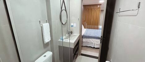 A compact hotel bathroom with a toilet, sink, and shower.