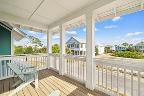 A covered porch with a view of neighboring houses and a clear sky.