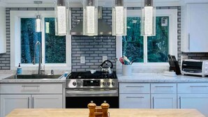 A modern kitchen with a central island, stainless steel appliances, and pendant lighting.