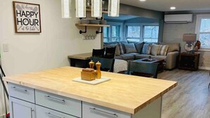 A modern kitchen with a central island, grey cabinets, and pendant lighting.