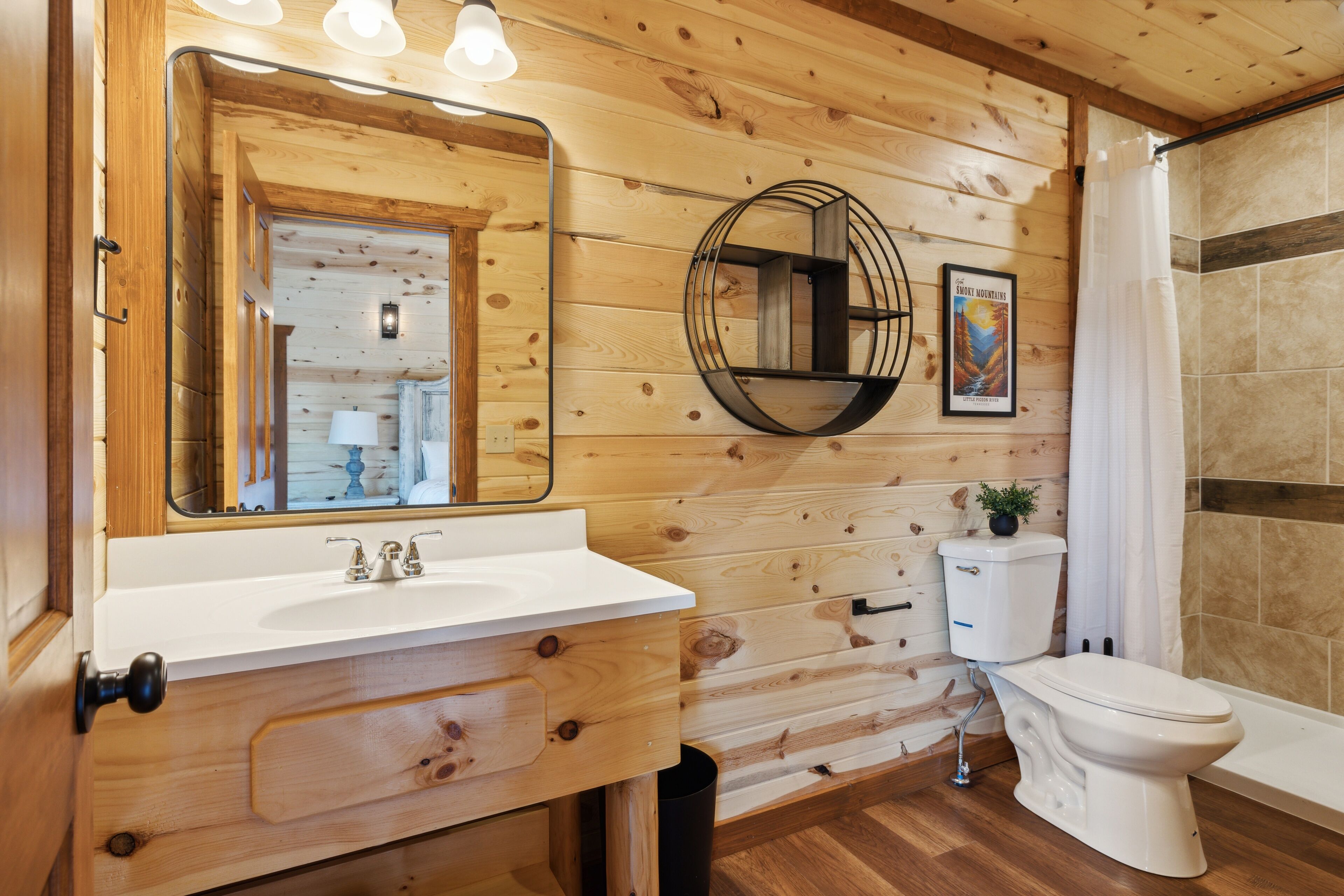 A wooden-paneled bathroom with a white sink, mirror, and toilet.