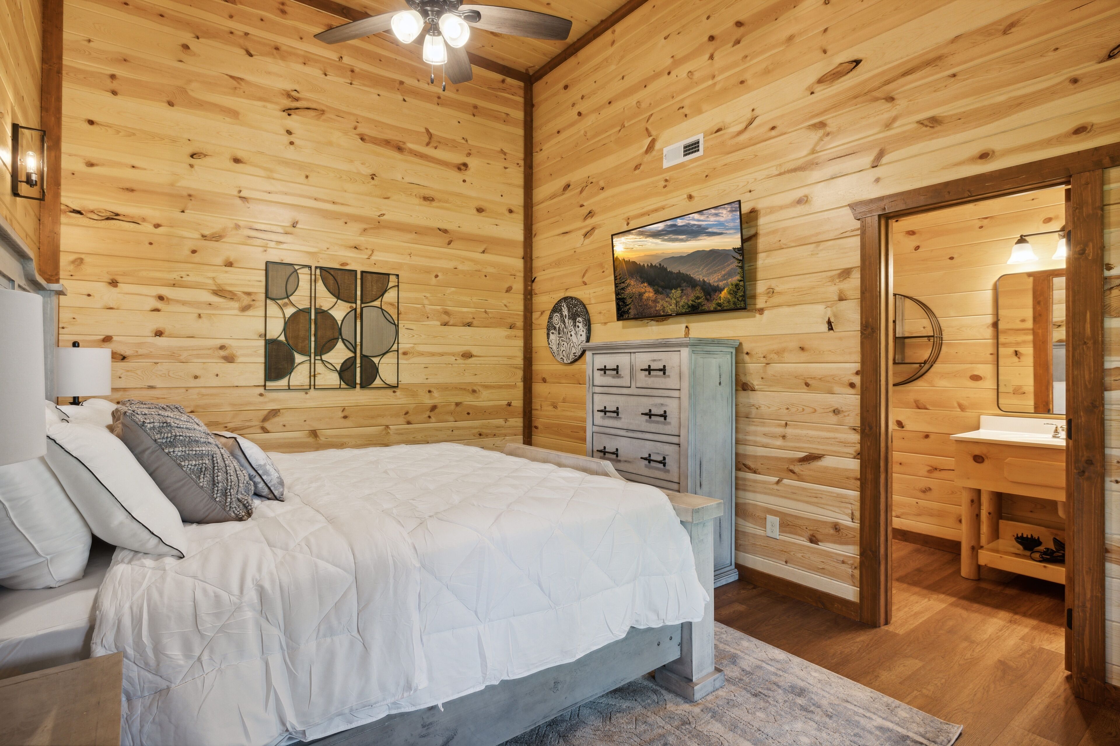 A wooden-paneled bedroom with a bed, dresser, and artwork.