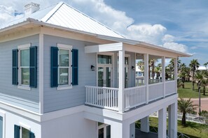 A white building with blue shutters, a balcony, and a covered porch. - Seaside Rendezvous - Private Home Across From Community Park 4 Bedroom Home by RedAwning (South Padre Island)