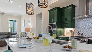 Una cucina moderna con mobili verdi, una grande isola con bevande e un piano cottura.