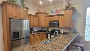 A kitchen with wooden cabinets, stainless steel appliances, granite countertops, and a window with decorative glass. - Island Time #4 2 Bedroom Condo by RedAwning (South Padre Island)