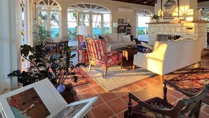 A spacious living area with a high ceiling, a fireplace, and large windows offering a view of the outdoors. - Big Hill - a luxurious haven that will not disappoint, View Sunrise, Dock (Elbow Cay)