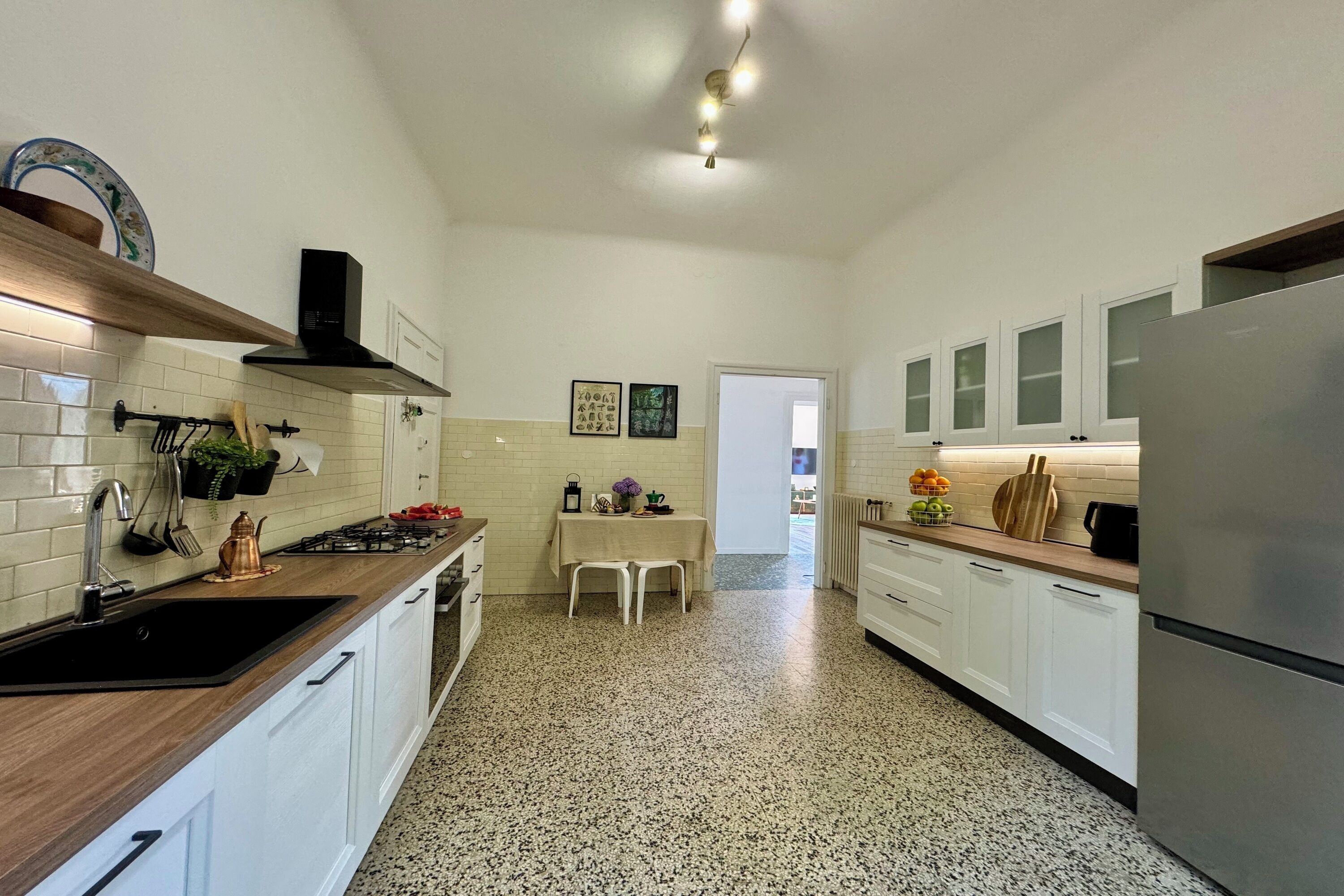 A modern kitchen with white cabinets, a granite countertop, and a stainless steel refrigerator.