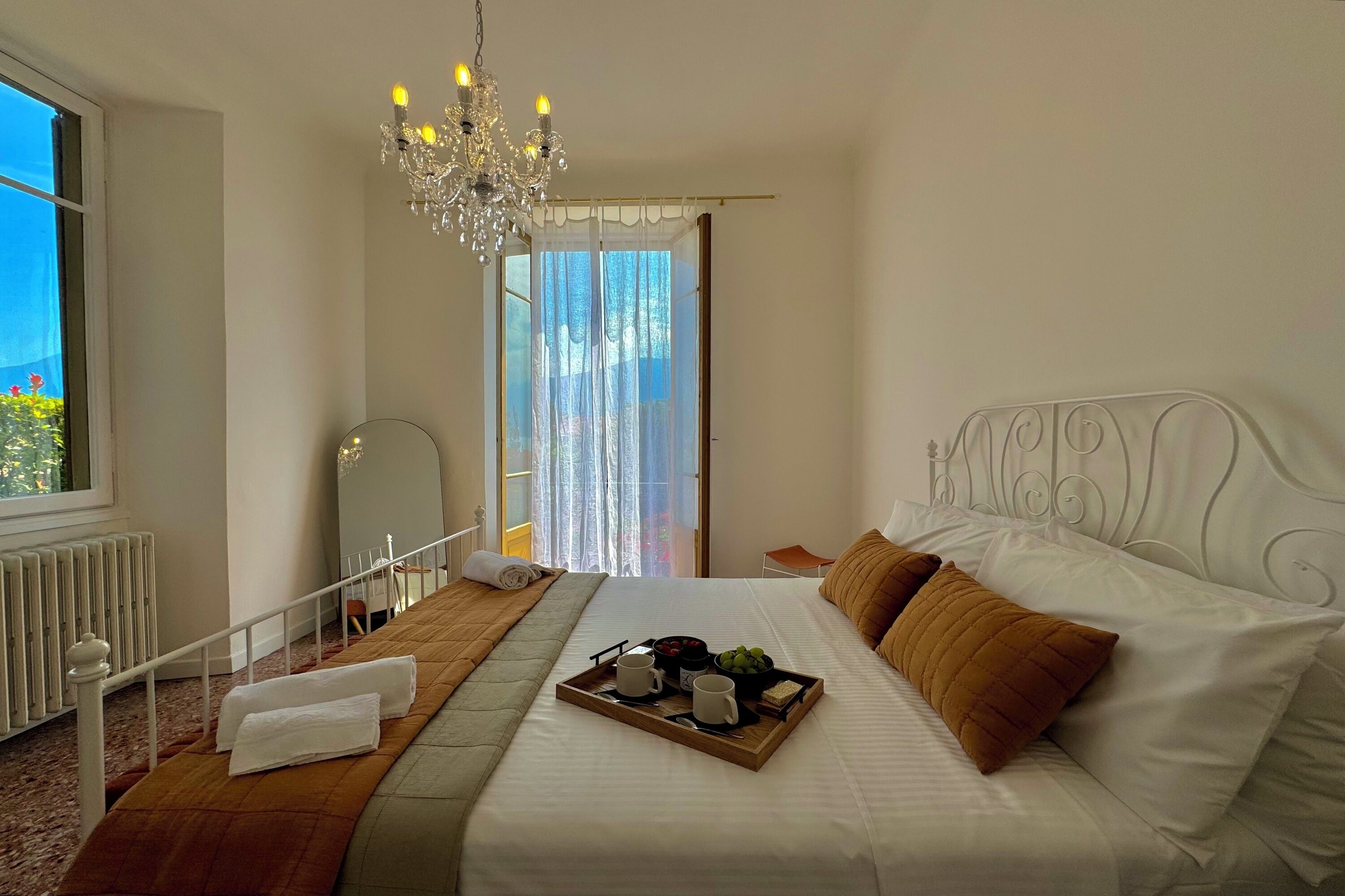 Una cama bien hecha con una bandeja de desayuno, un candelabro y vistas al exterior.