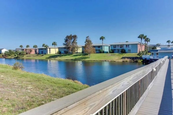 A waterfront property with a wooden deck, a calm lake, and colorful buildings.