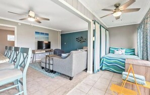 Cozy living space with a sofa, chairs, dining table, and TV, featuring a comfortable bed and a rug.