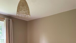 A bedroom with a wooden bed frame, a bedside table with a lamp, and a hanging light fixture.