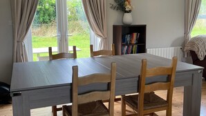 A dining area with a large table, four wooden chairs, and hanging pendant lights.
