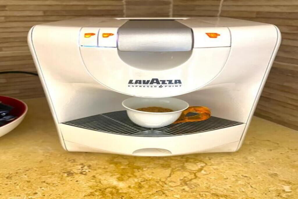 Une machine à expresso Lavazza avec une verseuse à café posée sur le bac d’égouttement.
