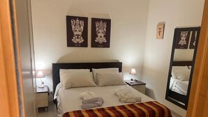 Een hotelkamer met een groot bed, twee nachtkastjes met lampen, een gestreept plaid en kunst aan de wanden.